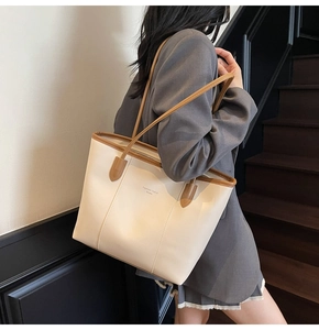 Detail of minimalist cream tote bag with brown leather handles and brand lettering