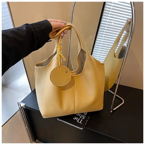 Détail du sac fourre-tout jaune en similicuir grainé avec breloque porte-monnaie ronde