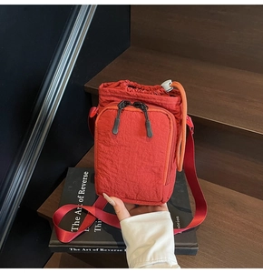 Detail of red wrinkled nylon crossbody bag with dual zipper pocket and drawstring closure