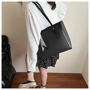 Detail of large black woven tote bag with a geometric scarf and leather shoulder strap