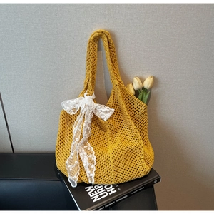 Détail du sac cabas en tricot jaune avec nœud en dentelle blanche et décoration tulipe