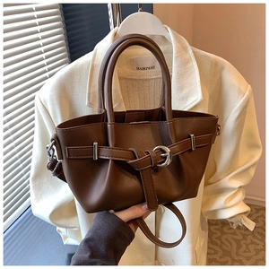 Détail d'un sac seau en cuir marron foncé avec boucles argentées et design plissé