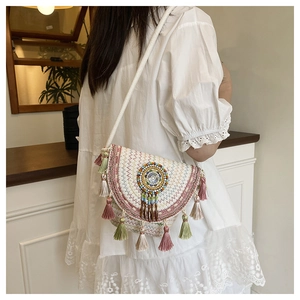 Ricami dettagliati e nappe colorate su una borsa a tracolla intrecciata in stile etnico