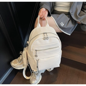 Close-up of white lychee texture leather backpack with mini pouch and silver zippers