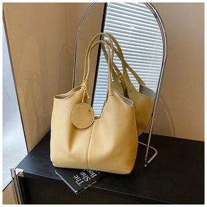 Détail du sac cabas jaune en cuir grainé avec étiquette ronde sur un bureau noir