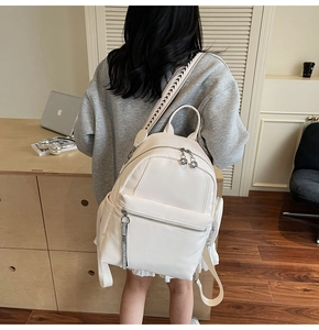 Detailed view of cream leather backpack featuring geometric arrow woven shoulder strap