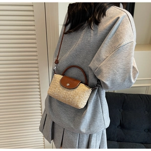 Detail of hand-woven straw crossbody bag with brown leather flap and magnetic metal clasp
