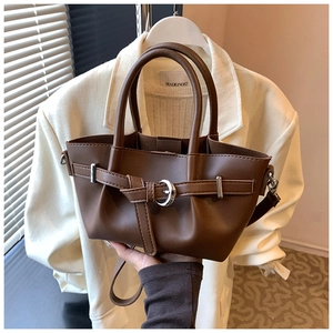 Gros plan d'un sac seau marron foncé avec boucle décorative et texture en cuir mat