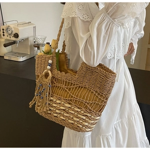 Detailed close-up of woven straw tote bag with evil eye tassels and rich textures