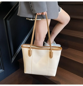 Detail of cream leather tote bag with brown handles and Fashion Trend brand lettering