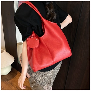 Détail du sac cabas rouge en cuir grainé avec pochette ronde porté par le mannequin