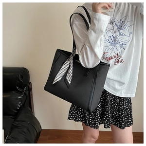 Detail of black faux leather tote bag with a chic houndstooth scarf on the handle