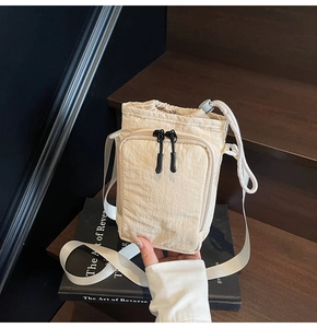 Detail of beige nylon drawstring bucket bag with pleated texture and zipper pocket
