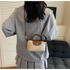Handmade woven straw bag with brown leather flap shown on model for size and scale
