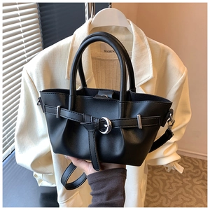 Détail du sac à main trapèze noir avec boucle circulaire argentée et bandoulière