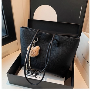 Litchi texture black leather tote bag displayed in a gift box with a plush bear charm