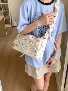 Sac bandoulière floral avec nœuds rouges et bandoulière froncée sur modèle