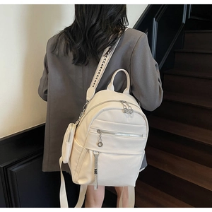 Close-up of off-white faux leather backpack with textured finish and geometric woven strap