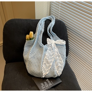 Détail du sac hobo bleu clair tricoté à la main avec un nœud en dentelle blanche