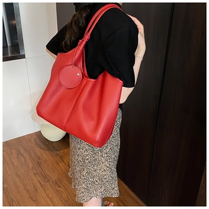 Détail du sac cabas rouge en cuir montrant la texture grainée et le design souple style hobo