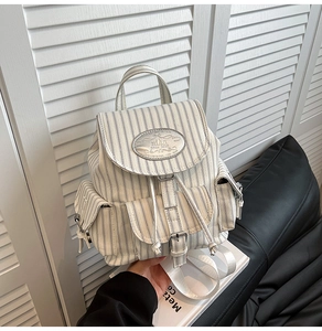 Detail des gestreiften Canvas-Rucksacks mit Schnallenverschluss und Metall-Logo