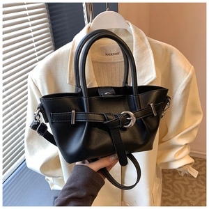 Détail du sac à main en cuir noir avec boucle argentée et poignée, style élégant