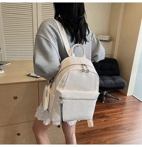 Close-up of white lychee texture leather backpack with front pocket and round charm