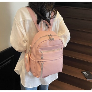 Detail of pink PU leather backpack with lychee texture and round coin purse charm