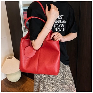Détail du sac cabas en cuir rouge texturé avec pendentif et finitions de couture