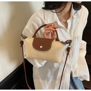 Detail of hand-woven straw bag with dark brown leather flap and long shoulder strap