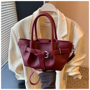 Détail d'un sac seau bordeaux en cuir avec poignée et boucle décorative élégante