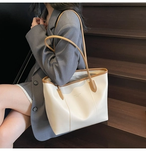 Detail shot of a vintage-style tote bag in cream and brown, featuring long shoulder straps
