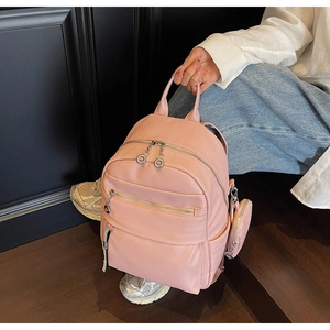 Detail of pink pebbled leather backpack with silver zippers and mini coin purse charm