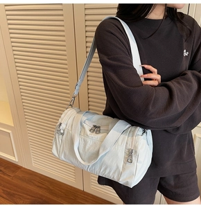 Detail view of light blue nylon travel bag showing durable fabric and adjustable strap