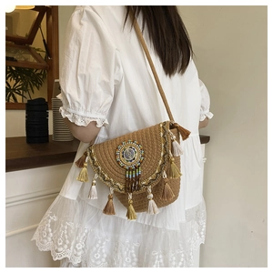 Dettaglio borsa a secchiello in paglia boho con perline colorate e nappe a balze