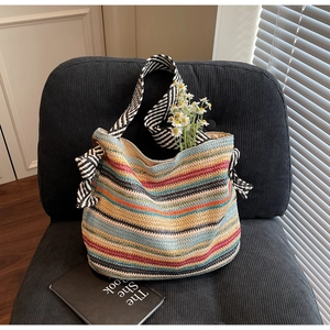 Dettaglio borsa tote a righe colorate con fiocco laterale e tracolla intrecciata