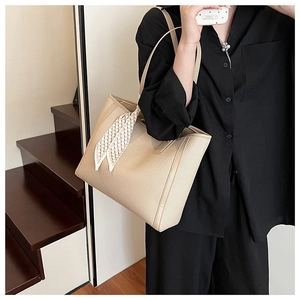 Detail of beige tote bag showing woven texture and black-white checkered scarf decoration
