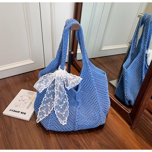 Détail du sac cabas en tricot bleu roi avec un grand nœud en dentelle blanche et maille