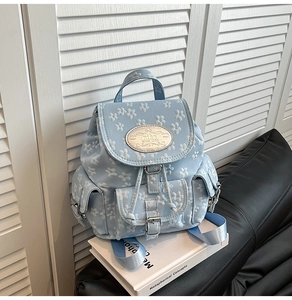 Detailansicht hellblauer Rucksack mit weißen Blumenstickereien und Metall-Markenlogo