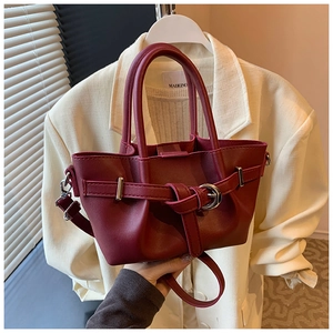 Gros plan sur un sac seau bordeaux en cuir avec boucles argentées et poignées cylindriques