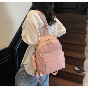 Detailed view of pink pebble leather backpack with silver zippers and V-pattern straps