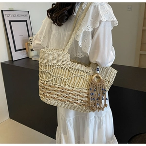 Detail of hand-woven straw tote with wave patterns and evil eye tassel charm