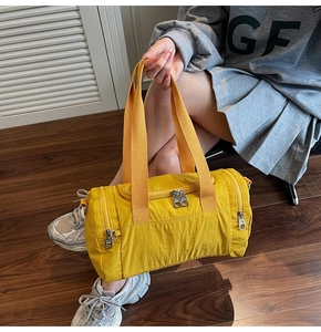 Detail of a bright yellow nylon travel bag showing durable handles and zipper pockets