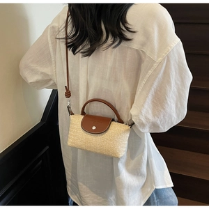 Detail of hand-woven straw crossbody bag with dark brown leather flap and silver buckle