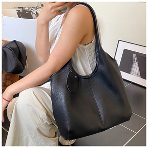 Détail du sac cabas Hobo noir texture litchi avec pendentif rond au style élégant