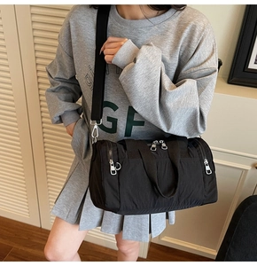 Detail of a black nylon barrel travel bag with adjustable straps and zippered pockets