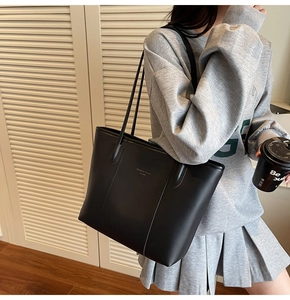 Close-up of minimalist black leather tote bag with gold lettering for daily office commute