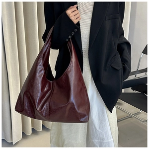 Detail der weinroten, glänzenden Hobo-Tasche mit Retro-Textur und Vintage-Halbmond-Stil