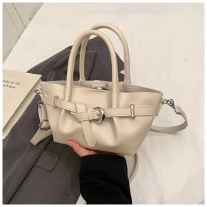 Vue de dessus d'un sac seau crème avec boucles argentées sur fond de literie