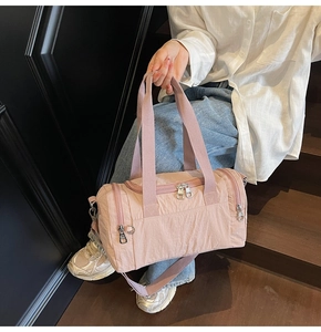 Detailed view of pink nylon travel bag with multiple zippers and adjustable shoulder strap